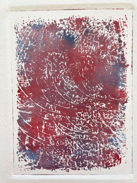 A4 sized ink print in reds and blues mixing into purples. It is marked with lines sweeping to the right.
