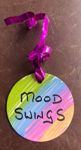 A colourful circle label with the words 'mood swing' on it. Purple foil ribbon. 