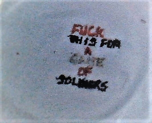 Using a handwritten pattern this cross stich by Pauline Heath reads 'f*ck this for a game of soldiers'. The lettering is all capitals and is in red, black and grey thread. 