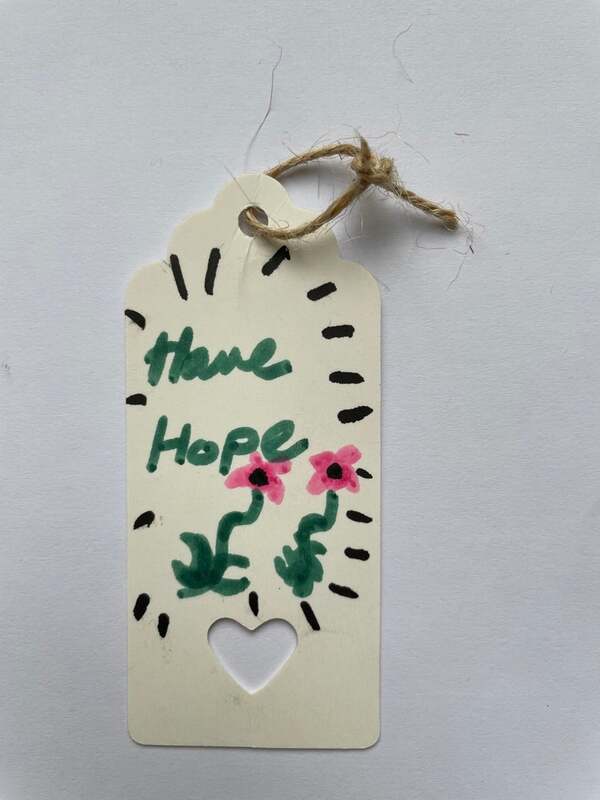 'Have Hope' handwritten with two pink flowers and green foliage on a white parcel label. Samantha Blackburn.