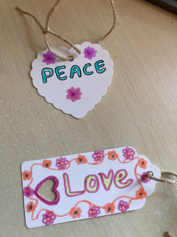 Two beautiful labels - a whote heart with the word 'peace' and pastel coloured flowers. And a whote oblong label with heart cut out shape and the word 'love' surrounded by a chain of flowers. Caroline Miles.