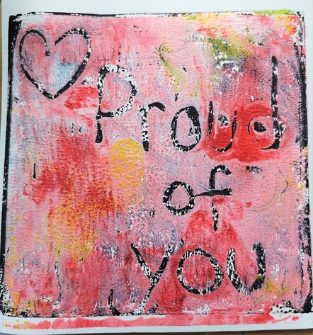 A black and white ink back ground has been overlaid with pink and small blended patches of yellow. A heart and the words 'proud of you' have been marked out from the pink revealing the black and white underneath.