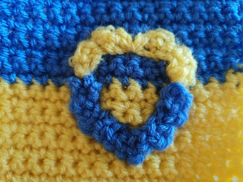 Crocheted Ukrainian flag with crocheted heart in opposite colours. Vici Wreford-Sinnott.