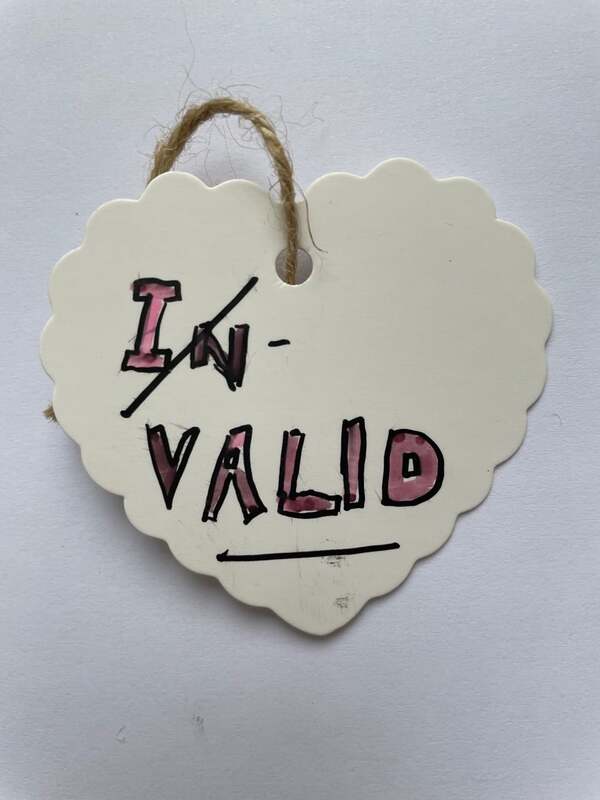 a white heart label with the word IN-VALID in black and red. The 'IN' is crossed out to leave the word VALID. Samantha Blackburn.