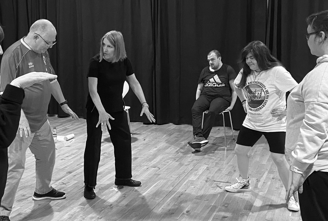 A group of learning disabled actors in an actor training session with Jacqueline Phillips, all stretching and testing out physicality. 