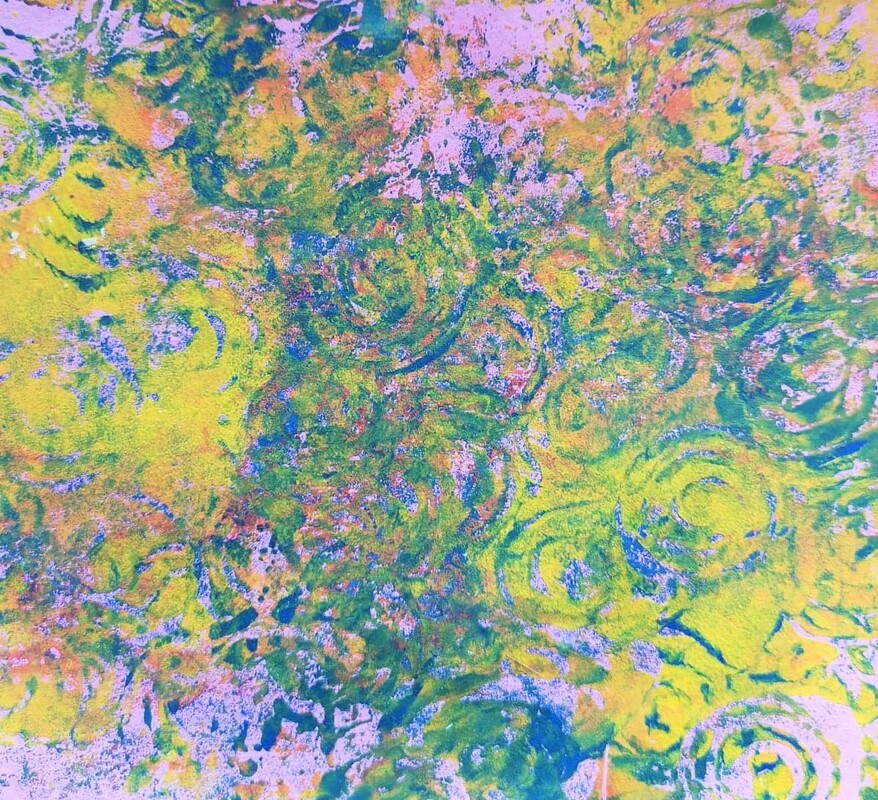 A pale pink background that has golden yellow sections to the middle left and lower right of the print. The centre section has been printed with a spiral motif wooden block using cobalt blue over and over giving a blue green effect. The blue green spirals have been lightly printed over the rest of the print but lets the golden yellow stand out beneath.