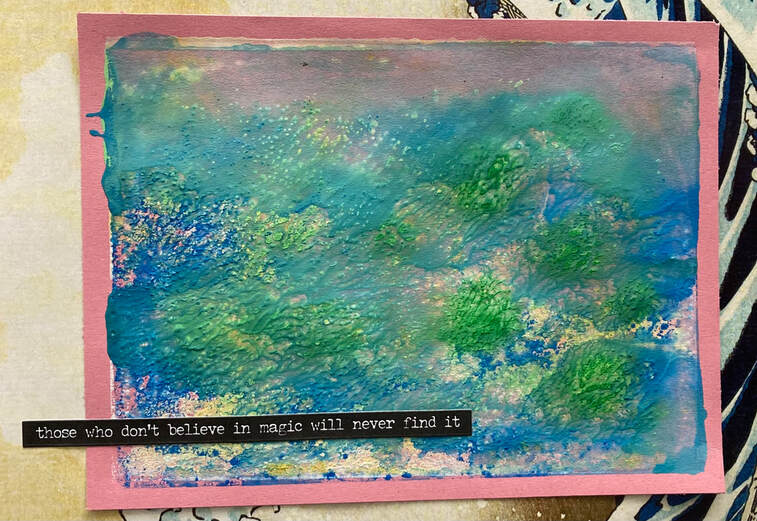 A blue and green ink print image which will suggest different things to different people. It could be seen as blue and gree sea, or a blue landscape with greenery in it. The print has been placed over patterned paper and has a line of text added, 'those who don't believe in magic will never find it'.