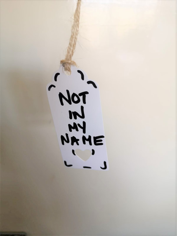 A white label with a cut out heart reads 'Not in my name'. Vici Wreford-Sinnott